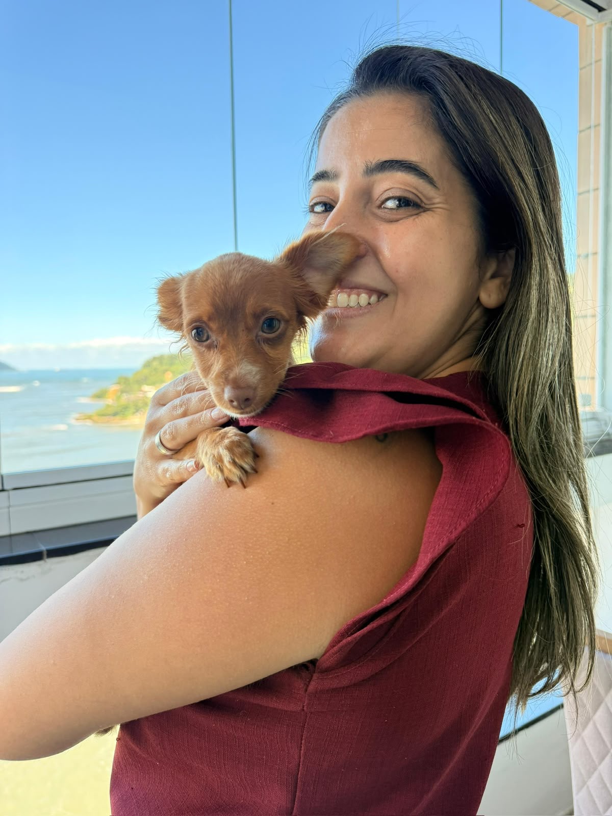 M.V. Nathana Carregoza segurando um filhote de cachorro no colo durante atendimento domiciliar
