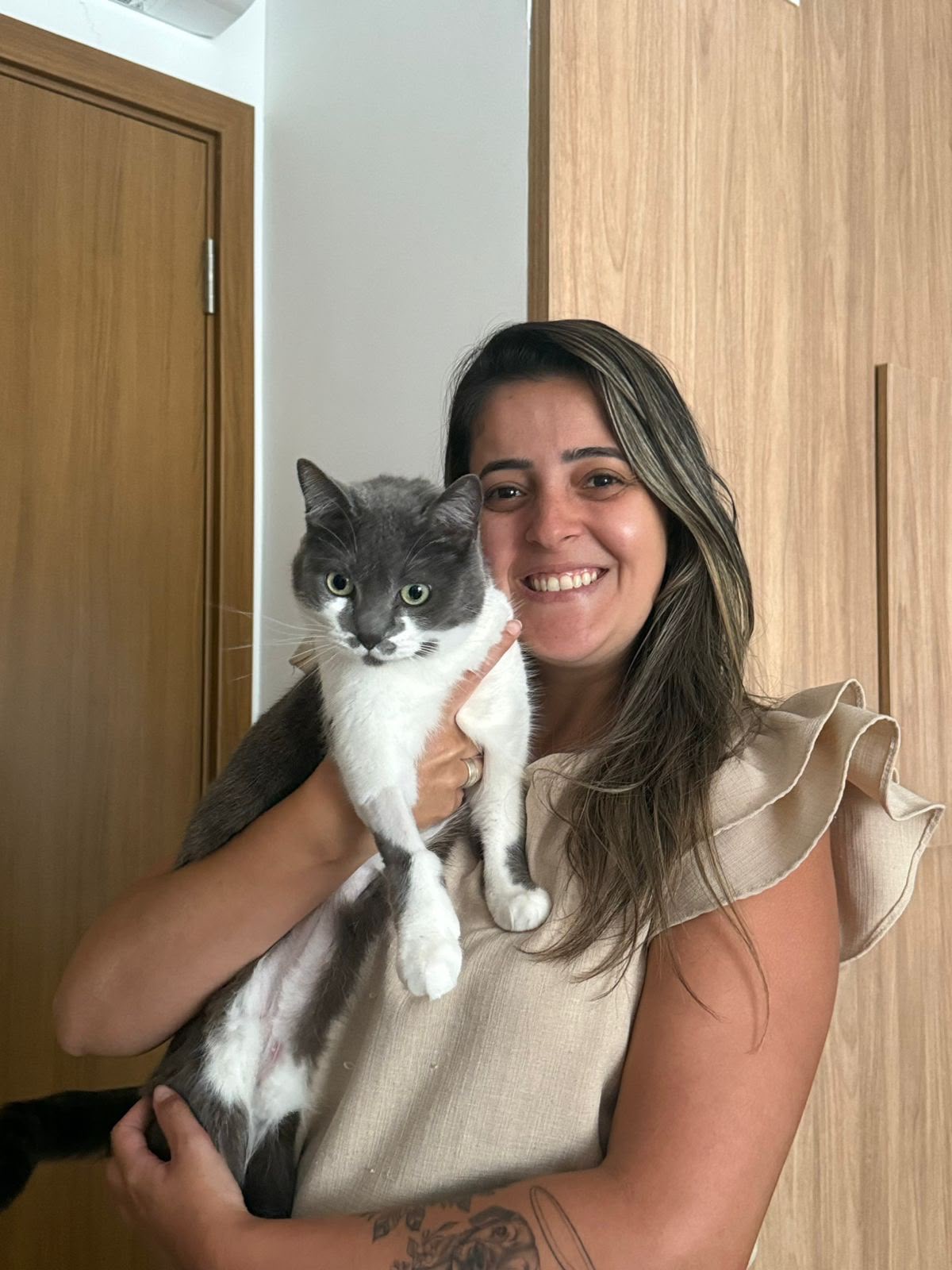 M.V. Nathana Carregoza segurando um gato cinza e branco durante atendimento domiciliar